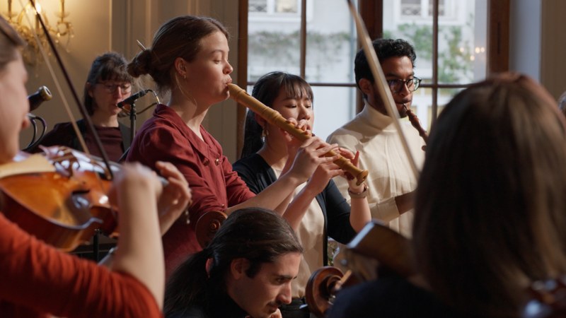 Eine Block-Flötistin in einem Orchester umgeben von Streichern