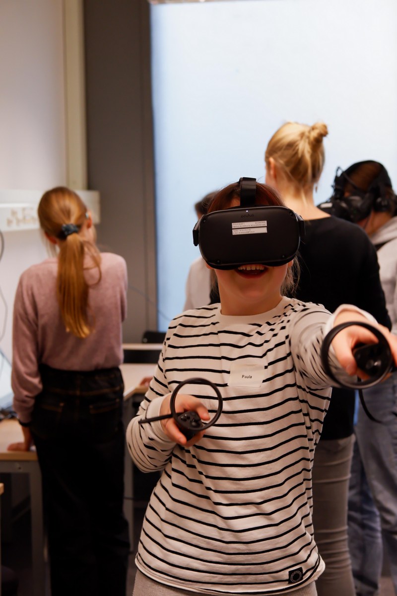 Ein Mädchen hat ein VR-Headset auf und bewegt sich im virtuellen Raum