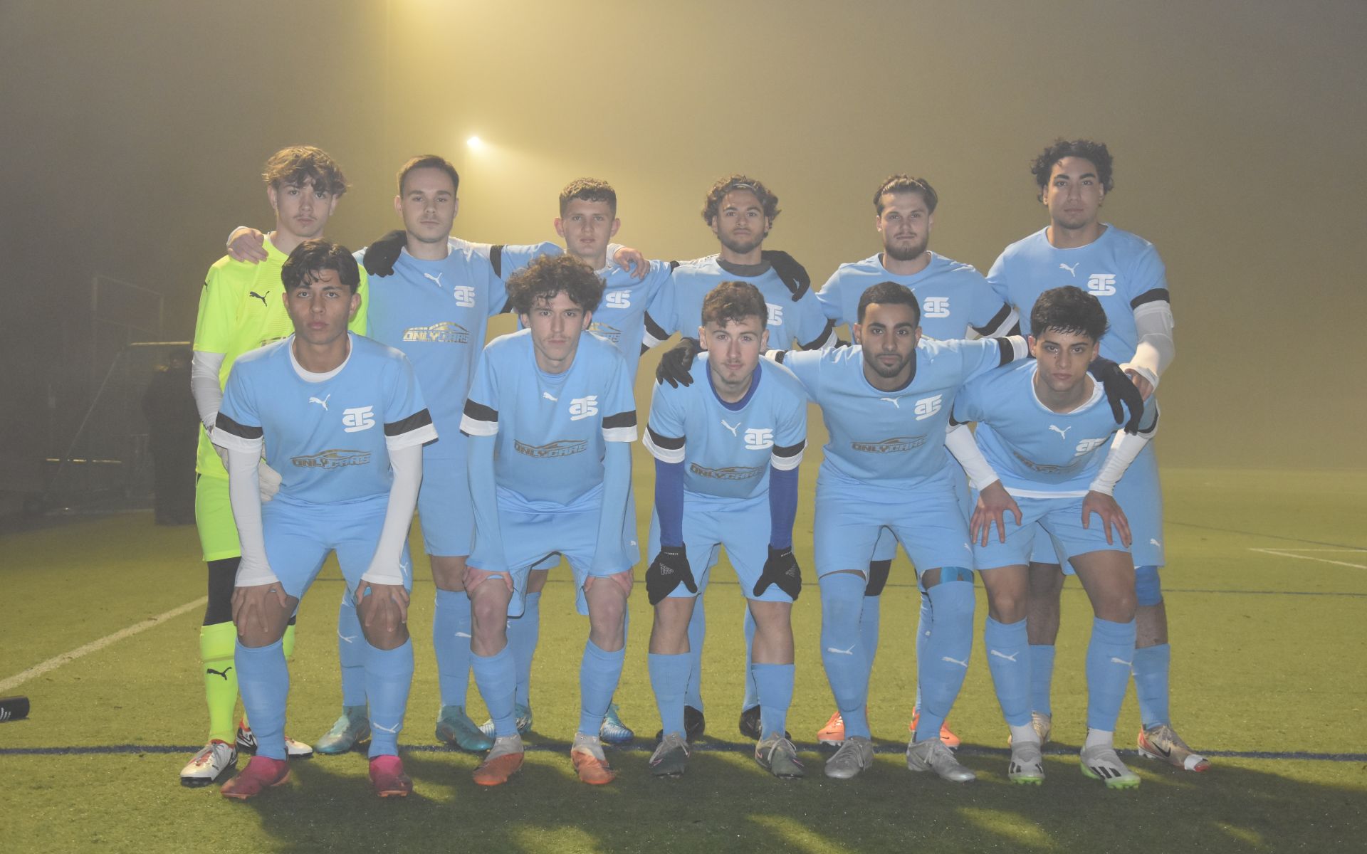 Mannschaftsbild des Teams von Simpletransfer. 10 Feldspieler in hellblauen Trikots und Hosen mit Simpletransfer-Logo und ein Torhüter posieren auf dem Platz für ein Foto.