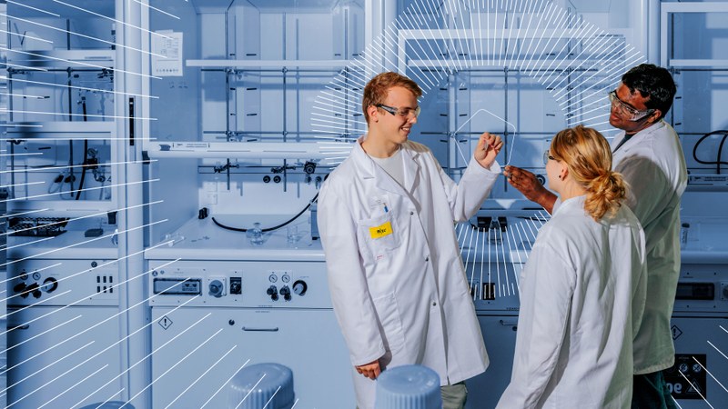 Drei Personen in Laborkitteln stehen in einem Labor